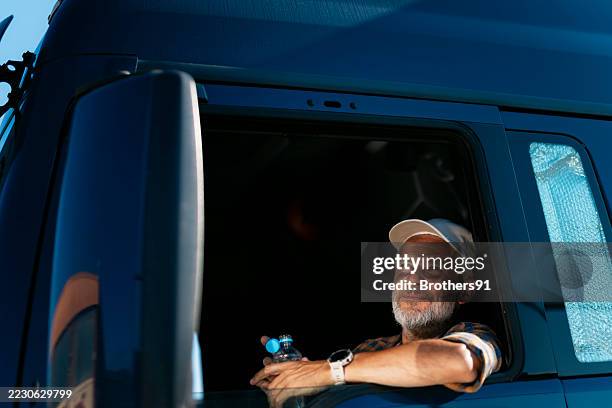 truck driver resting and enjoying the view from his cabin - vrachtwagenchauffeur stockfoto's en -beelden