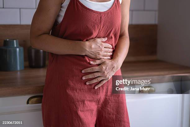 primer plano de las manos de la mujer sobre su estómago angustiada - incómodo fotografías e imágenes de stock
