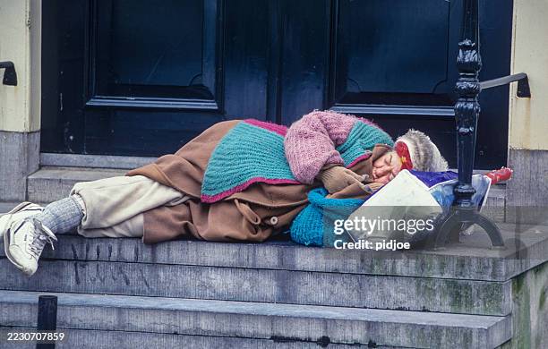 a homeless person sleeps on the street under a blanket - homelessness stock pictures, royalty-free photos & images