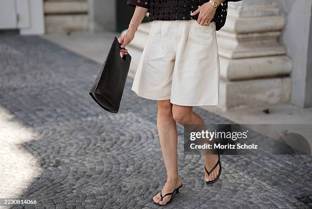 Anouk Delphine is seen wearing an H&M dark brown crochet t-shirt with three-quarter sleeves; a pair of beige Cos bermuda pants; a black squared...
