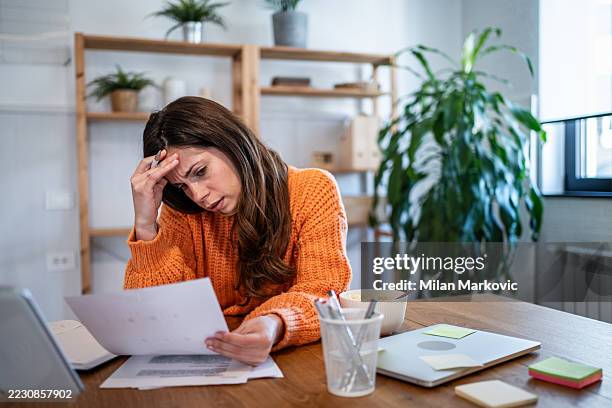 stressed young woman reading documents at home - collect payment stock pictures, royalty-free photos & images