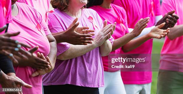 group of adults at fundraiser for breast cancer research - cancer awareness ribbon stock pictures, royalty-free photos & images