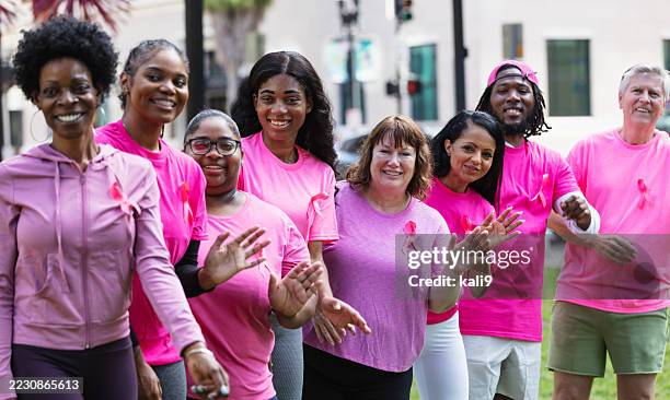 group of adults at fundraiser for breast cancer research - cancer awareness ribbon stock pictures, royalty-free photos & images