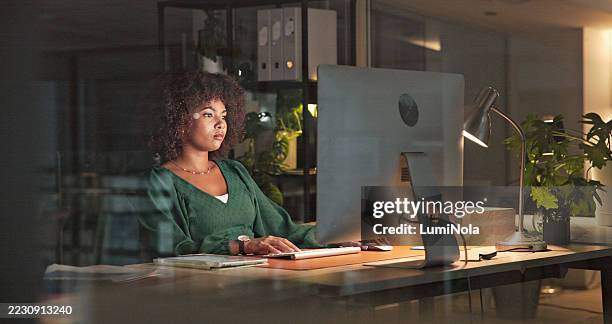 profesional enfocado que trabaja hasta altas horas de la noche en un entorno de oficina moderno - penumbra fotografías e imágenes de stock