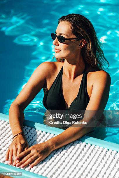 elegant woman enjoying summer in a refreshing swimming pool - swimming costume stock pictures, royalty-free photos & images