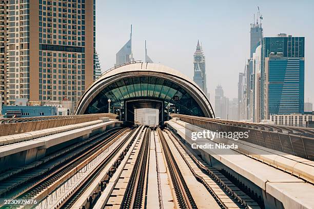 moderne bahngleise zwischen dubais ikonischen wolkenkratzern an einem klaren tag - bahntunnel stock-fotos und bilder
