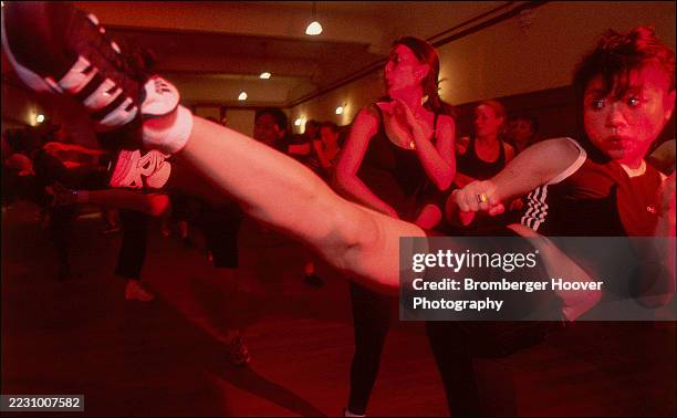 View of a woman as she practices kicks in a Taekwondo martial arts class at the Gorilla Sports gym, San Francisco, California, 1998.