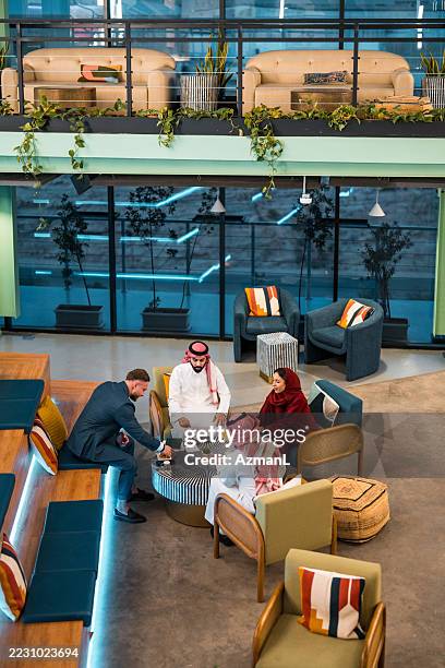 middle eastern business professionals in modern office meeting with young caucasian partner - arab culture stock pictures, royalty-free photos & images