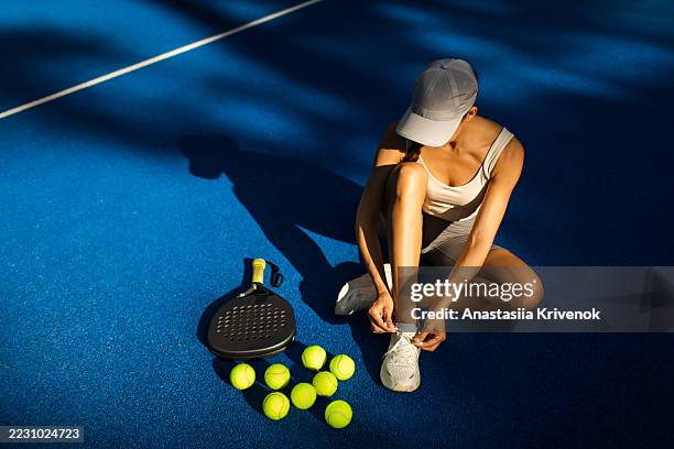 woman preparing for padel game on blue court with equipment - raqueta fotografías e imágenes de stock