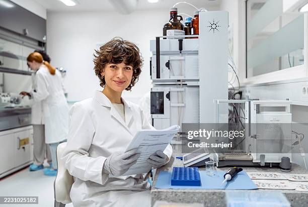 mid adult female scientist in white lab coat working in modern laboratory - scientist portrait stock pictures, royalty-free photos & images