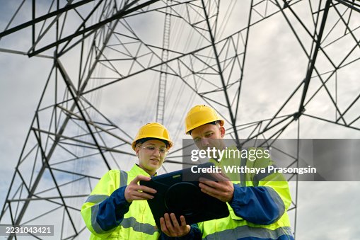 Electrical workers using digital tablet while inspecting power lines Electrical workers using digital tablet while inspecting power lines