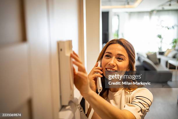 woman using intercom at home answering a call - intercom stock pictures, royalty-free photos & images