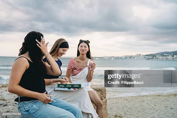 young women eating pizza by the sea in ibiza - ibiza island stock pictures, royalty-free photos & images