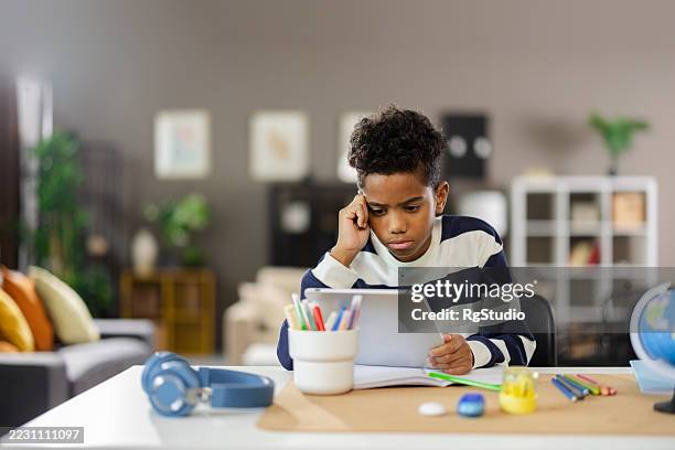 estudiante enfocado haciendo la tarea en la tableta en casa - instrumento de navegación fotografías e imágenes de stock
