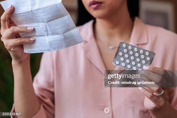 woman holding pack of pills and medication leaflet - hormone therapy stock pictures, royalty-free photos & images