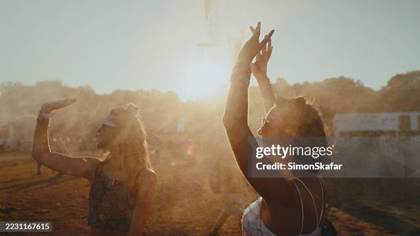 young caucasian women dancing in mist at music festival - traditional festival stock pictures, royalty-free photos & images