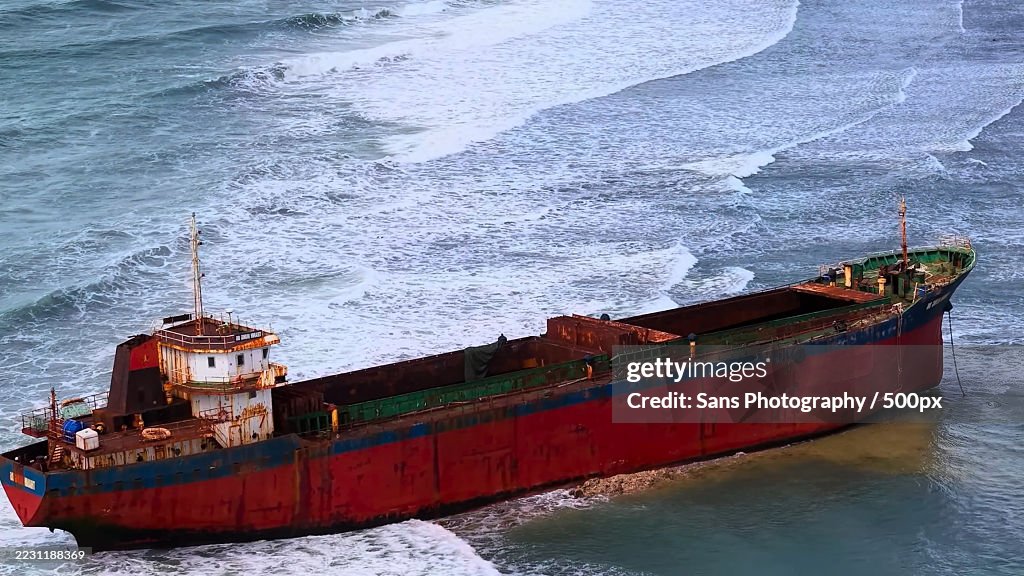 Rusty Cargo Ship Navigating Through Ocean Waves