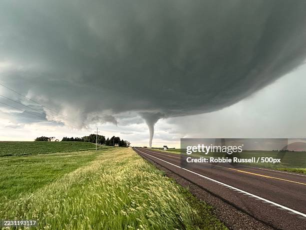 dramatic tornado looms over rural landscape - tornado stockfoto's en -beelden