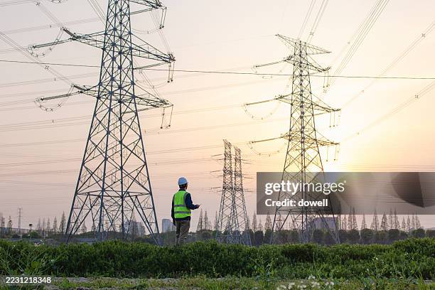 asian male engineer working under pylon - electricity substation stock pictures, royalty-free photos & images