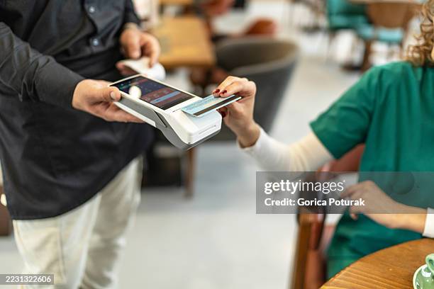nurse paying with contactless credit card in cafe - point of sale stock pictures, royalty-free photos & images