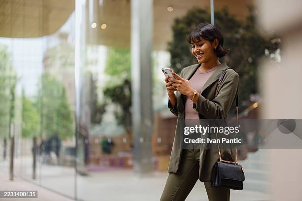 young businesswoman using smartphone in urban setting - female likeness stock pictures, royalty-free photos & images