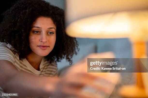 attractive latina woman turning off the light in bedroom at night before sleep. young female feeling happy and relaxed, resting and enjoying a peaceful holiday weekend at home in a dark room. - elektrische lampe stock-fotos und bilder