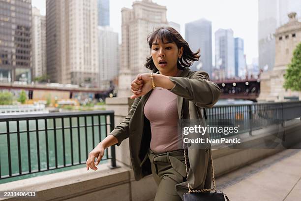 geschäftsfrau, die zu spät auf die armbanduhr in chicago schaut - auf die uhr sehen stock-fotos und bilder