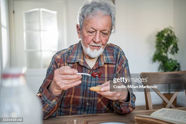 älterer mann, der ein einfaches frühstück zu hause genießt - einzelner senior stock-fotos und bilder