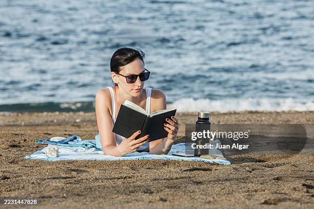 woman reading a book on the beach - sea breeze cocktail stock pictures, royalty-free photos & images