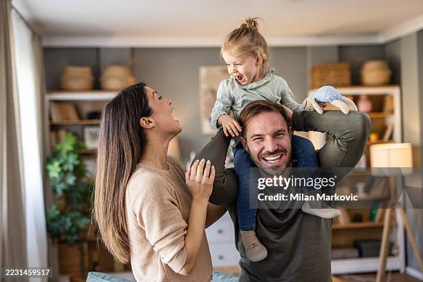 happy family playing together at home: father carrying daughter on shoulders - comfortabel stockfoto's en -beelden
