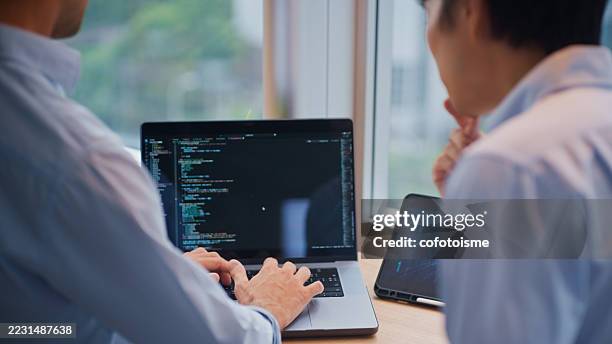 close-up of software developers reviewing code on laptop during collaboration session in modern office. - server engineer stock pictures, royalty-free photos & images