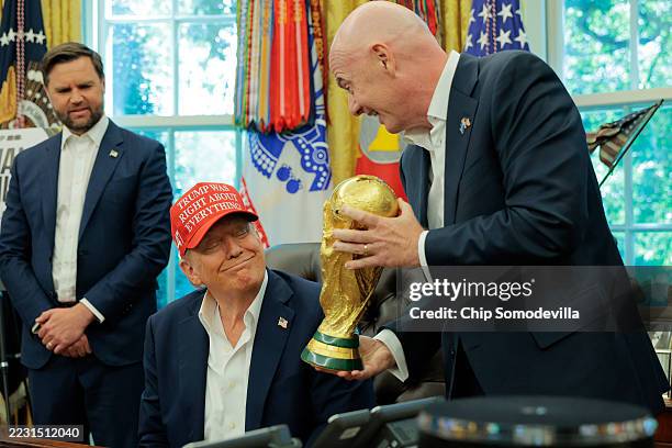 President Gianni Infantino shows U.S. President Donald Trump the World Cup Trophy in the Oval Office as Vice President JD Vance looks on August 22,...