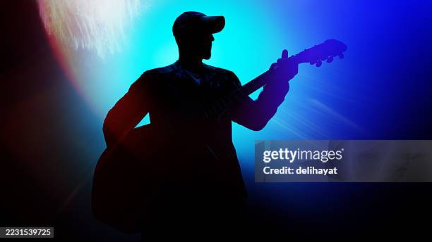 silhouette of a guitarist on stage. man playing guitar back lit with some lens flare from stage lights - pop music stock pictures, royalty-free photos & images
