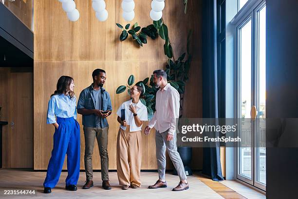 group of colleagues socializing in a modern and bright office lobby - happy colleagues doing team building activity imagens e fotografias de stock
