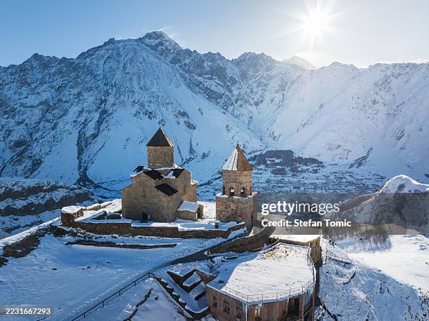 vista drone della chiesa della trinità di gergeti e delle vette del caucaso - georgia caucaso del sud foto e immagini stock
