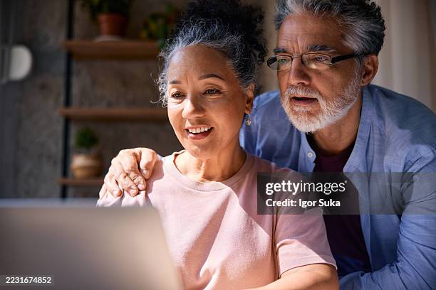 senior couple using laptop at home - couple looking at computer screen stock pictures, royalty-free photos & images