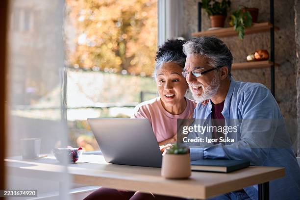 überraschtes älteres paar, das zu hause auf laptop schaut - old monitor computer stock-fotos und bilder