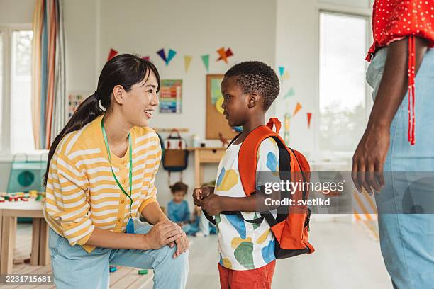 preschool teacher in classroom greeting new student - preschool student stock pictures, royalty-free photos & images