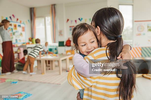 preschool teacher in classroom greeting new student - kinderopvang stockfoto's en -beelden