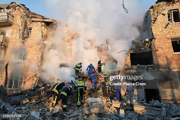 Firefighters douse flames at a residential building while rescuers search the rubble for victims after a Russian ballistic missile strike on August...
