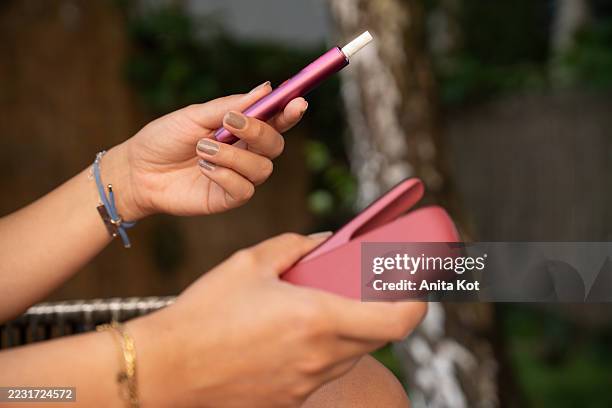female hands holding an e-cigarette and charger - produto relacionado com tabaco imagens e fotografias de stock