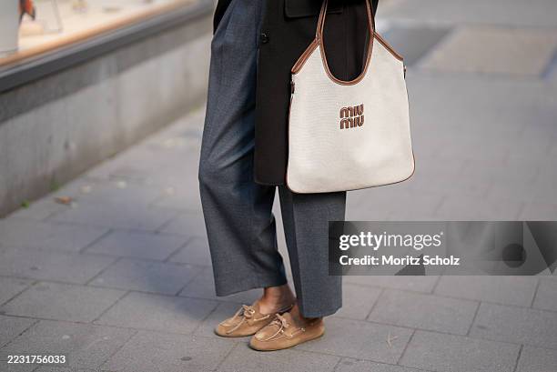 Patricia Wirschke is seen wearing a pair of Rossi elegant gray ankle length pants; she carries a beige Miu Miu Ivy cotton canvas and leather bag with...