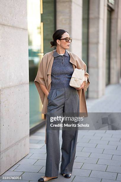 Patricia Wirschke is seen wearing a Cos wool blend cape in camel hue with a sewn on scarf; a grey knitted mohair polo with three buttons and collar...