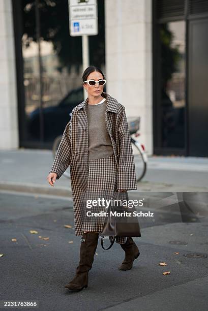 Patricia Wirschke is seen wearing a checked beige and brown long trench coat paired with a knee length tiered skirt of the same pattern; a greige...