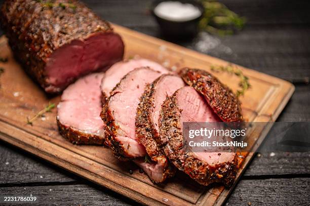 viande rôtie juteuse tranchée sur une planche à découper en bois avec assaisonnements - rosbif photos et images de collection