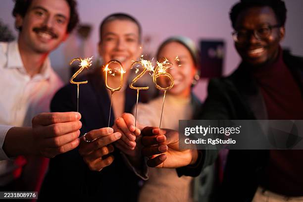 amigos celebrando la víspera de año nuevo con bengalas mostrando 2026 - new year fotografías e imágenes de stock