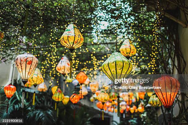 colorful traditional vietnamese lanterns hanging outdoors. illuminated at evening - vietnamese culture stock pictures, royalty-free photos & images