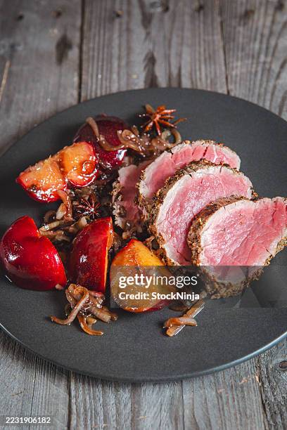 tender beef fillet served with roasted plums and caramelized onions - tenderloin stock pictures, royalty-free photos & images
