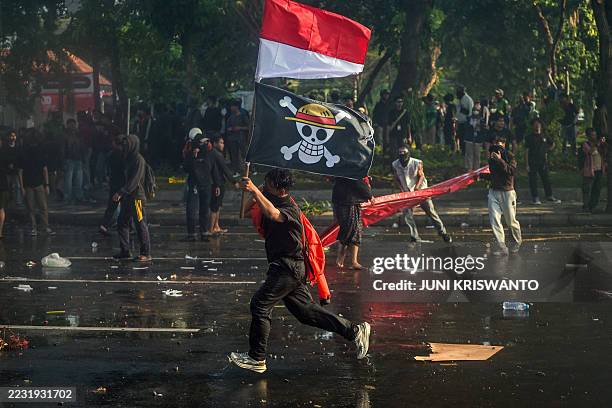 Demonstrator carries Indonesia's national flag and a pirate flag from the Japanese anime 'One Piece' an internet trend used to criticise government...