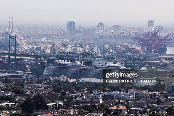 Cruise ship sits in a.berth near the Vincent Thomas Bridge at the Port of Los Angeles as cargo shipping containers stand on the horizon in Los...